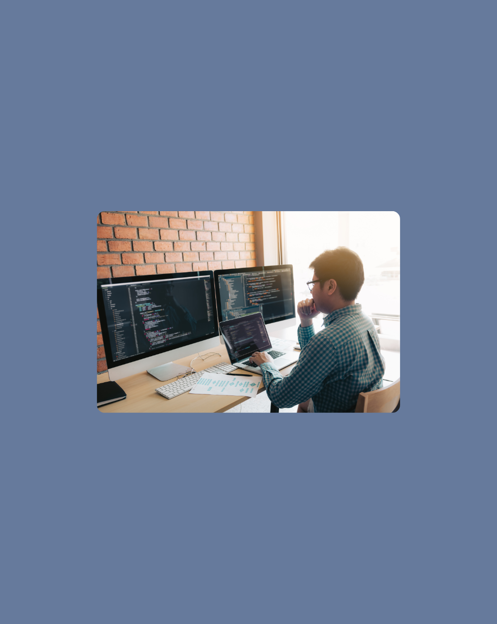 Image of a developer looking closely at his computer screens